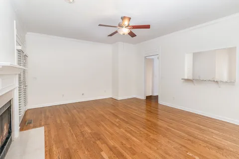 a view of an empty room with wooden floor and a ceiling fan