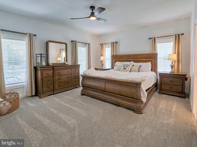 a spacious bedroom with a bed a dresser and windows