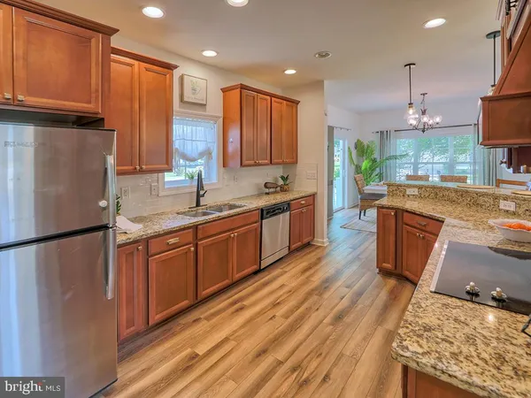 a kitchen with stainless steel appliances granite countertop a refrigerator a sink dishwasher a stove with wooden cabinets and floor