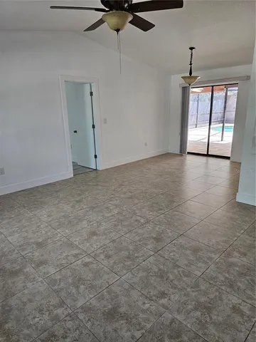 an empty room with chandelier fan and windows