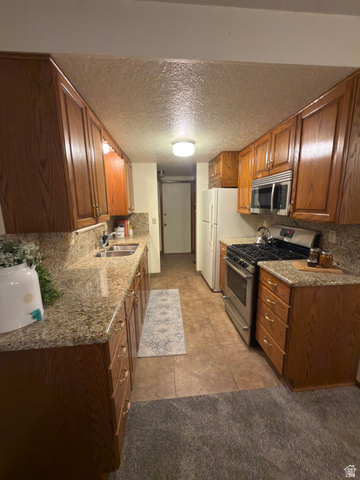 1164 East Mountain Road Logan, UT 84321 - Photo 37 of 45 Galley kitchen featuring wood-finish cabinetry, stone-finish countertops, stainless steel appliances including a range and microwave, and tile flooring