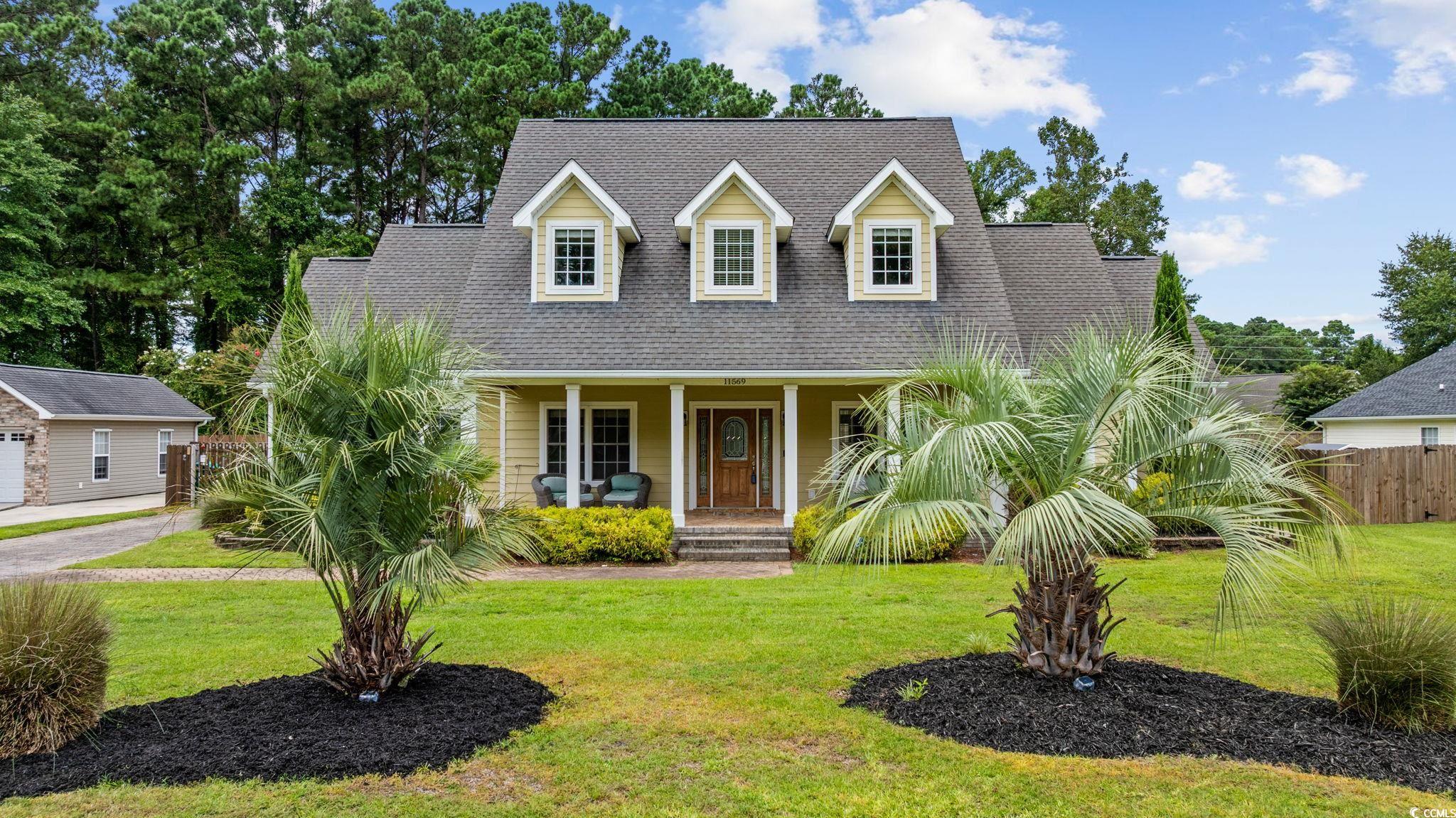 11569 Bay Drive Little River, SC 29566 - Photo 1 of 40 New england style home featuring roof with shingles and a porch