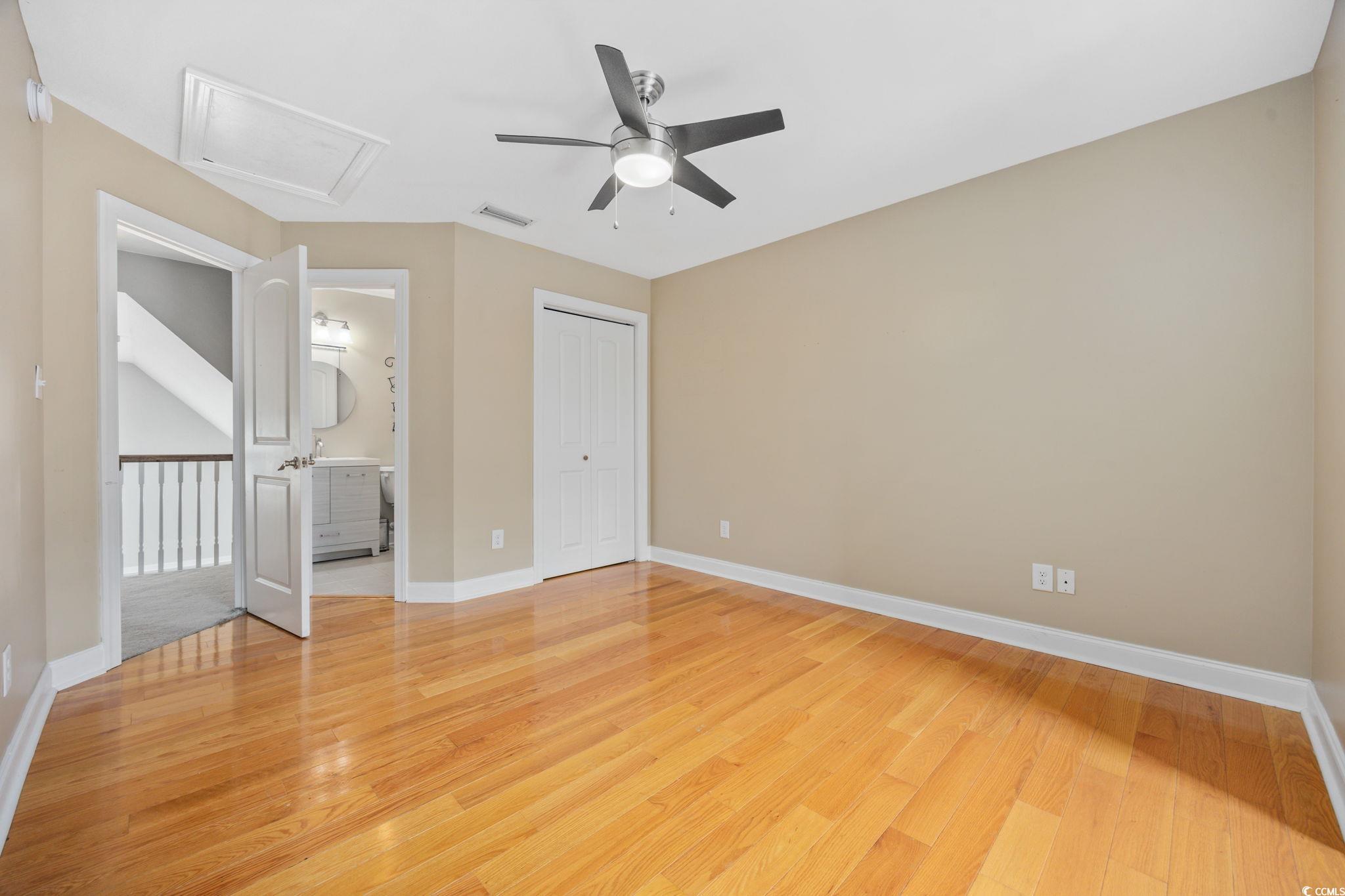 11569 Bay Drive Little River, SC 29566 - Photo 23 of 40 Unfurnished bedroom with light wood-style flooring, attic access, a closet, a ceiling fan, and connected bathroom