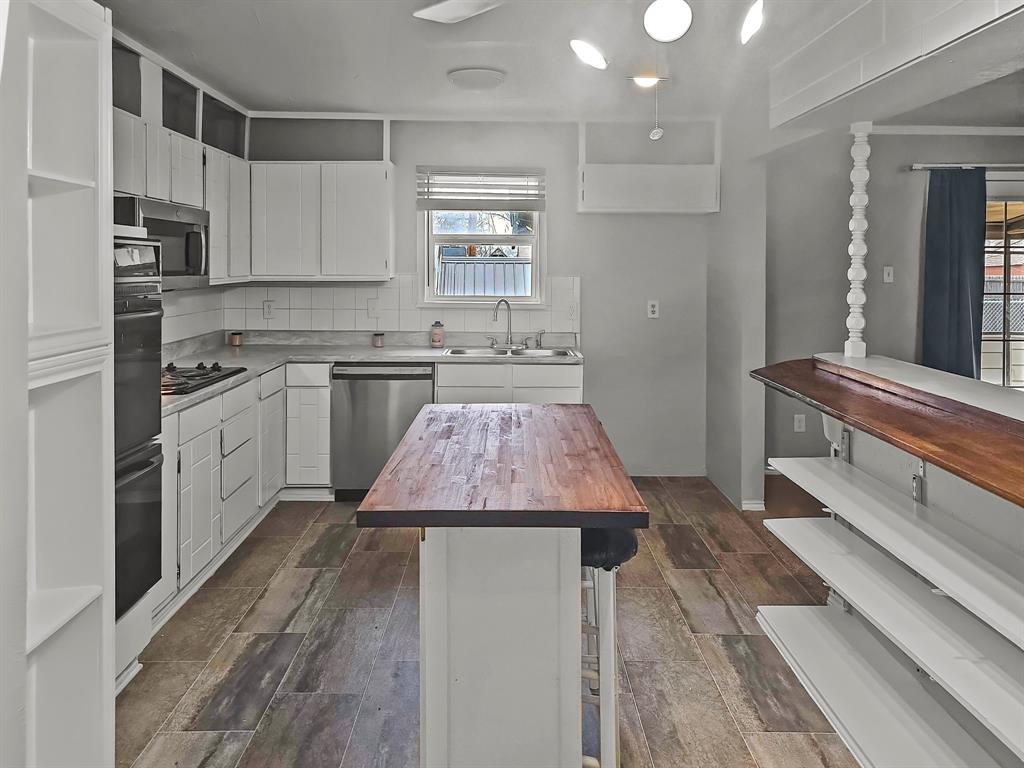 701 Idlewilde Drive Lewisville, TX 75067 - Photo 3 of 13 Kitchen with wood counters, appliances with stainless steel finishes, white cabinets, backsplash, and a breakfast bar