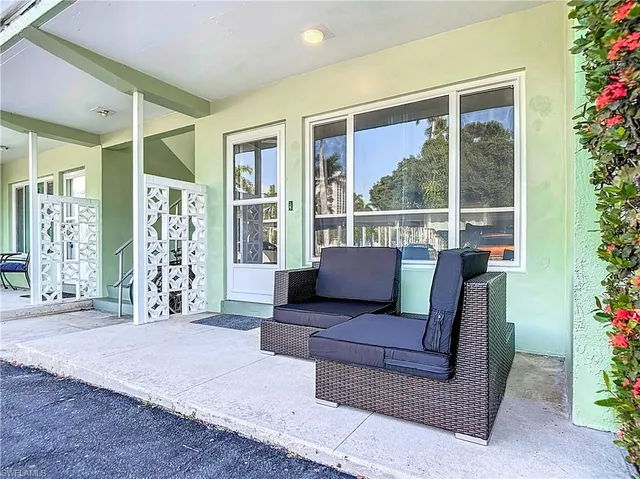 a view of a patio with couches chairs potted plants and floor to ceiling window and potted plants