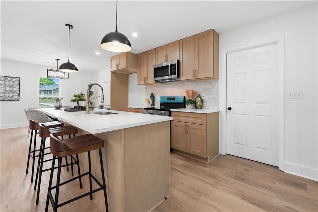 1808 Singer Way Lithonia, GA 30058 - Photo 11 of 37 a kitchen with stainless steel appliances kitchen island a white counter top space a sink and a wooden floor