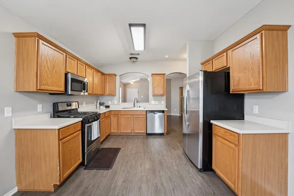 a large kitchen with stainless steel appliances granite countertop wooden floors a stove and a microwave