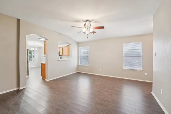 a view of an empty room with window and wooden floor