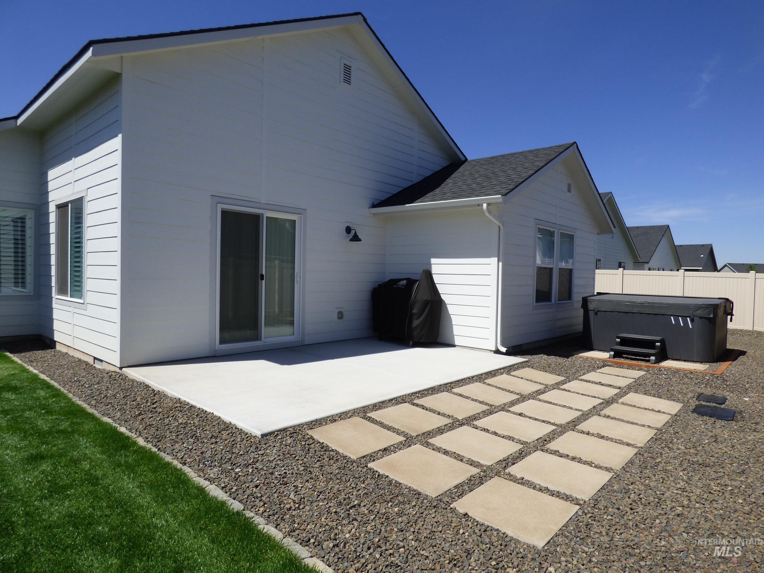 2708 East Buckaroo Drive Kuna, ID 83634 - Photo 47 of 48 Backyard patio featuring a sliding glass door, concrete pad, paver stone walkway, gravel landscaping, and a manicured lawn