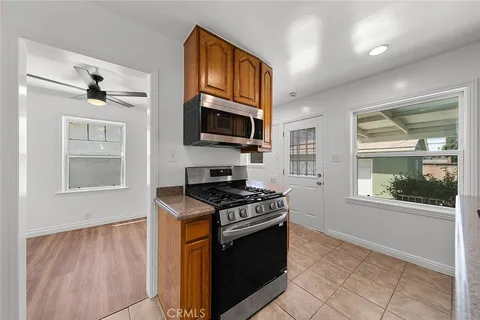 a kitchen with stainless steel appliances granite countertop a stove top oven a sink a dining table and chairs