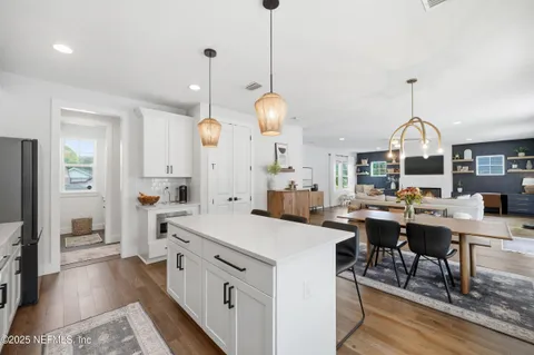 a open kitchen with stainless steel appliances granite countertop a stove a sink a dining table and chairs with wooden floor