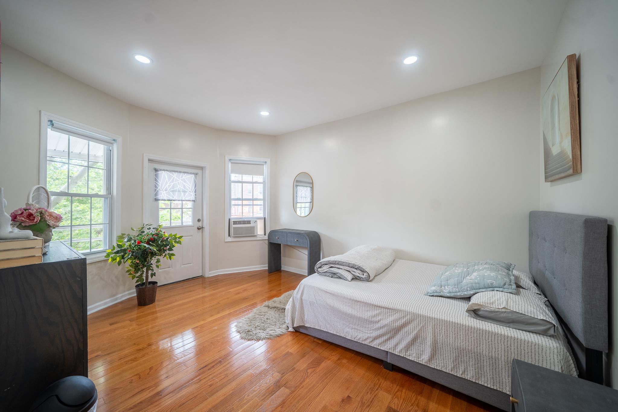 104-21 Lefferts Boulevard Queens, NY 11419 - Photo 25 of 29 a spacious bedroom with a bed and wooden floor