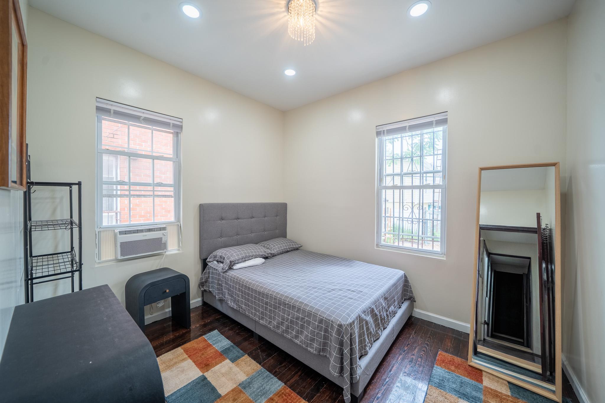 104-21 Lefferts Boulevard Queens, NY 11419 - Photo 10 of 29 a bedroom with a bed and a chandelier