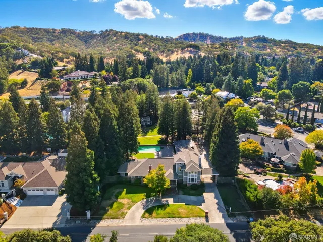 an aerial view of a house with a swimming pool a yard and mountain view in back