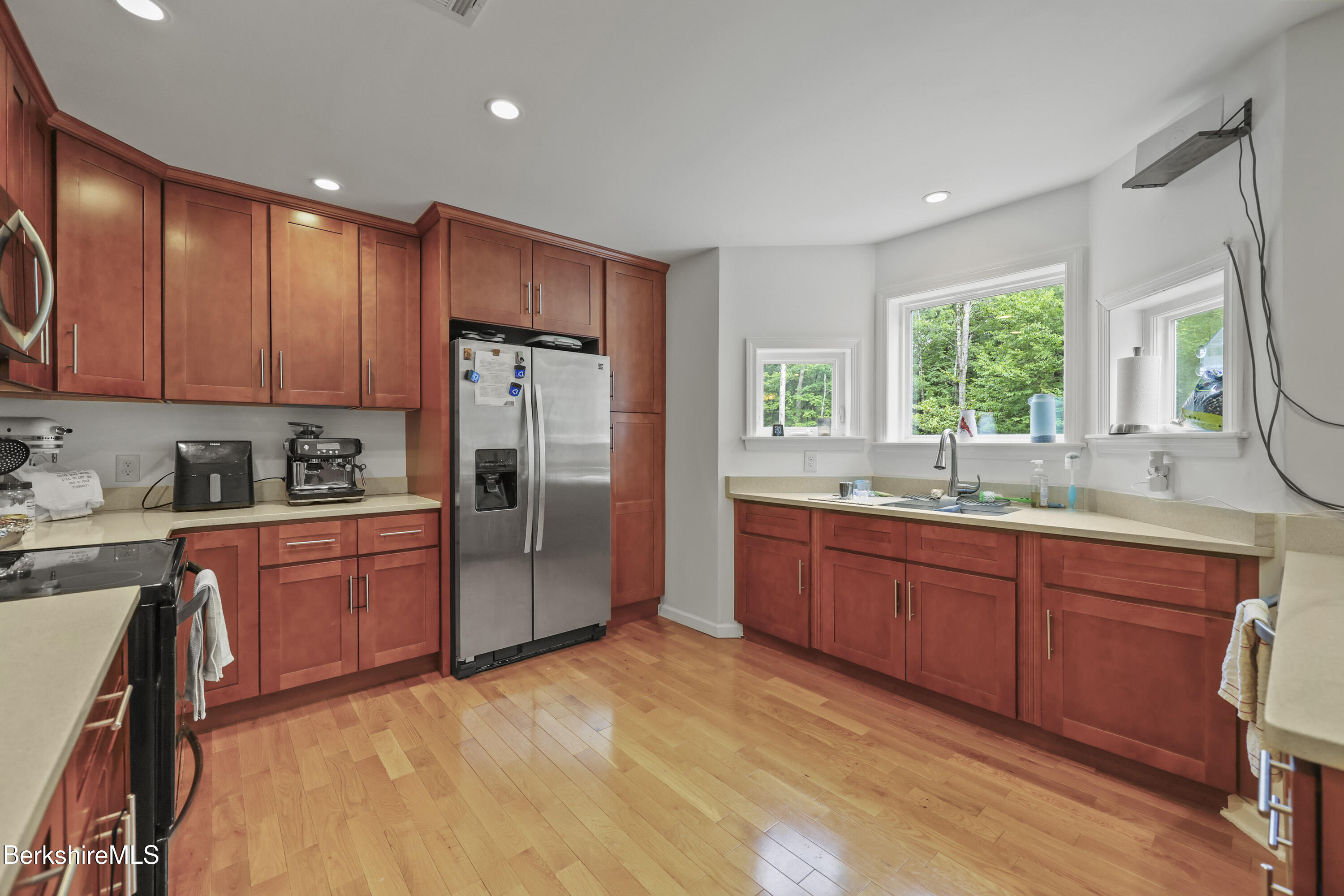 a kitchen with stainless steel appliances granite countertop a refrigerator a sink dishwasher a stove a washer and dryer with wooden floor