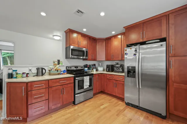 a large kitchen with stainless steel appliances granite countertop a sink and dishwasher a stove with wooden floor