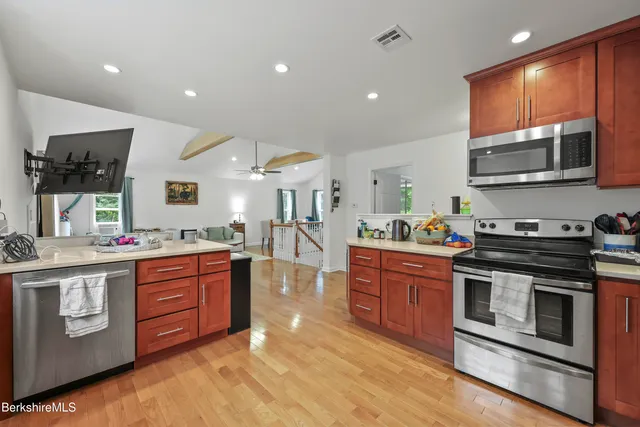 a kitchen with stainless steel appliances granite countertop a stove top oven a sink dishwasher and cabinets with wooden floor