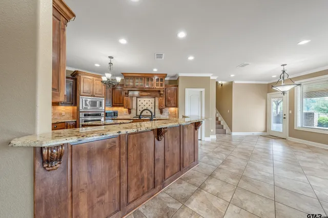 a view of a kitchen with kitchen island granite countertop wooden cabinets and stainless steel appliances