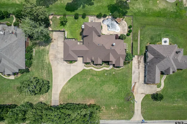 an aerial view of residential houses with outdoor space and trees