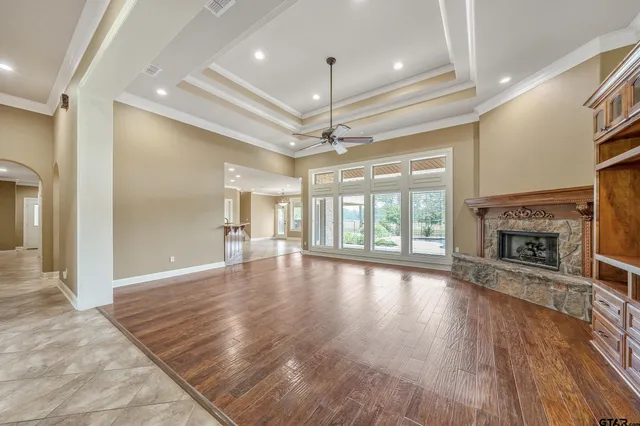 an empty room with wooden floor fireplace and windows