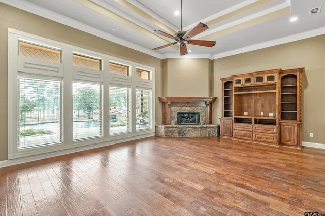 an empty room with wooden floor fireplace and a window