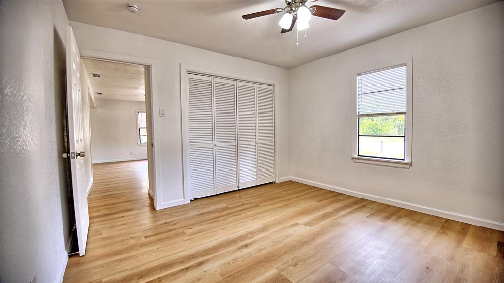607 Baylor Street Nocona, TX 76255 - Photo 16 of 23 an empty room with wooden floor chandelier fan and windows
