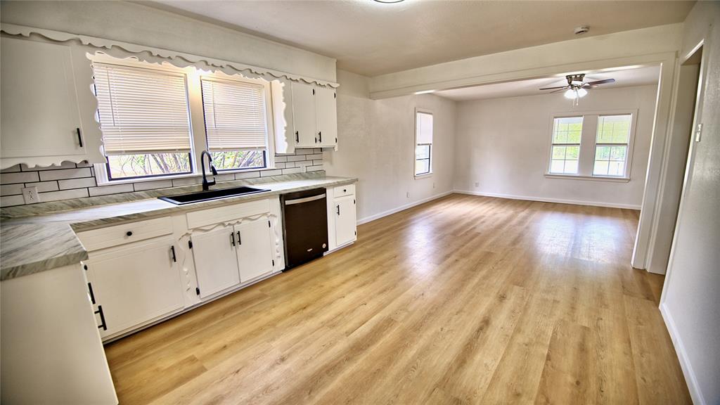 607 Baylor Street Nocona, TX 76255 - Photo 7 of 23 a large kitchen with cabinets wooden floor and a window