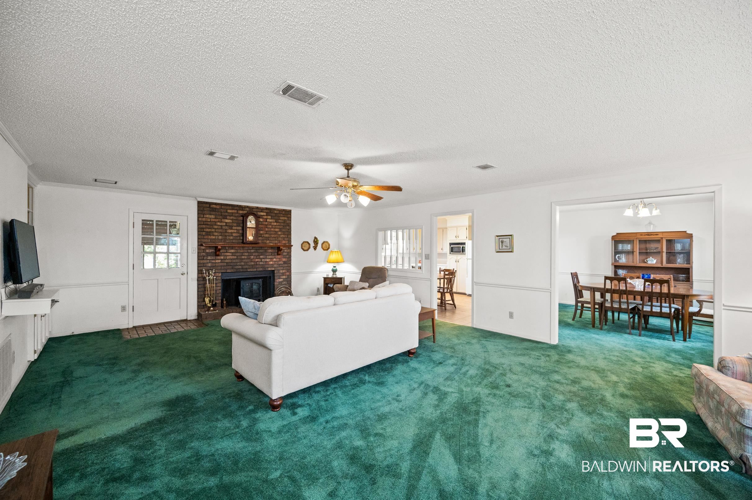15600 Fackler Road Loxley, AL 36551 - Photo 47 of 51 Living room featuring a fireplace, dark carpet, ceiling fan with notable chandelier, and a textured ceiling