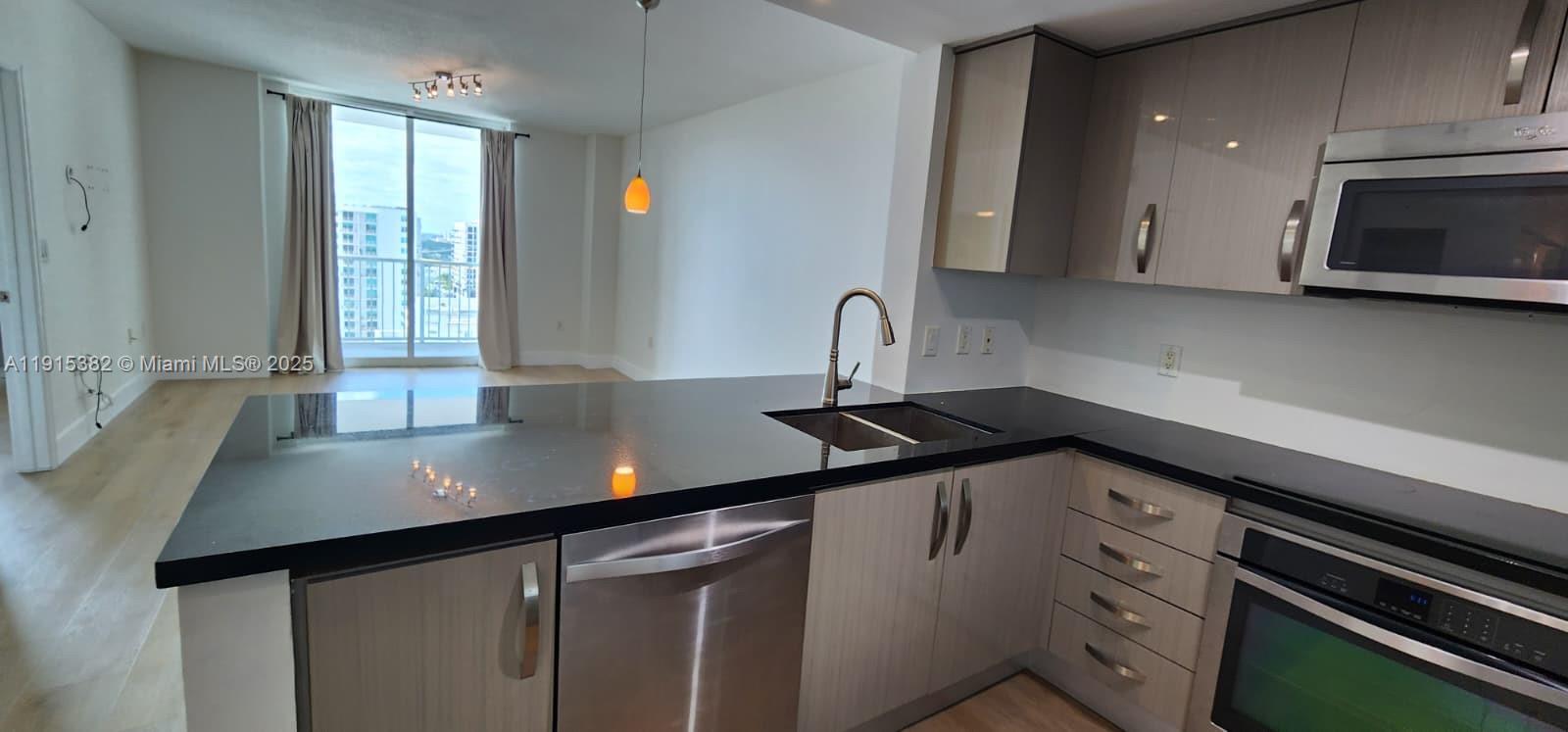 1250 South Miami Avenue, Unit 1911 Miami, FL 33130 - Photo 4 of 23 a kitchen with granite countertop a sink cabinets and stainless steel appliances