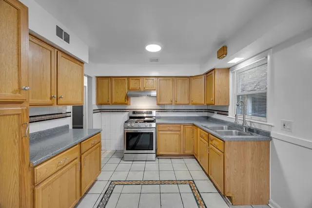 a kitchen with stainless steel appliances granite countertop a sink a stove and a refrigerator