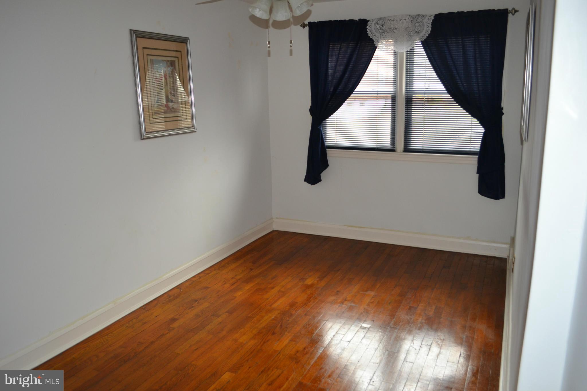 203 Grove Park Road Baltimore, MD 21225 - Photo 13 of 23 an empty room with wooden floor and windows