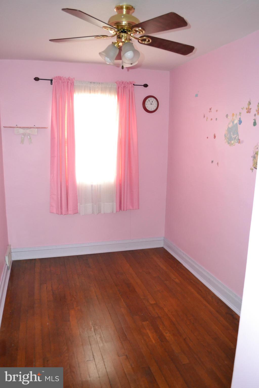203 Grove Park Road Baltimore, MD 21225 - Photo 14 of 23 an empty room with wooden floor and fan