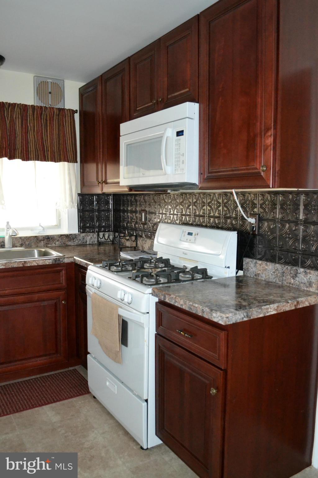 203 Grove Park Road Baltimore, MD 21225 - Photo 6 of 23 a kitchen with granite countertop a sink stove and microwave