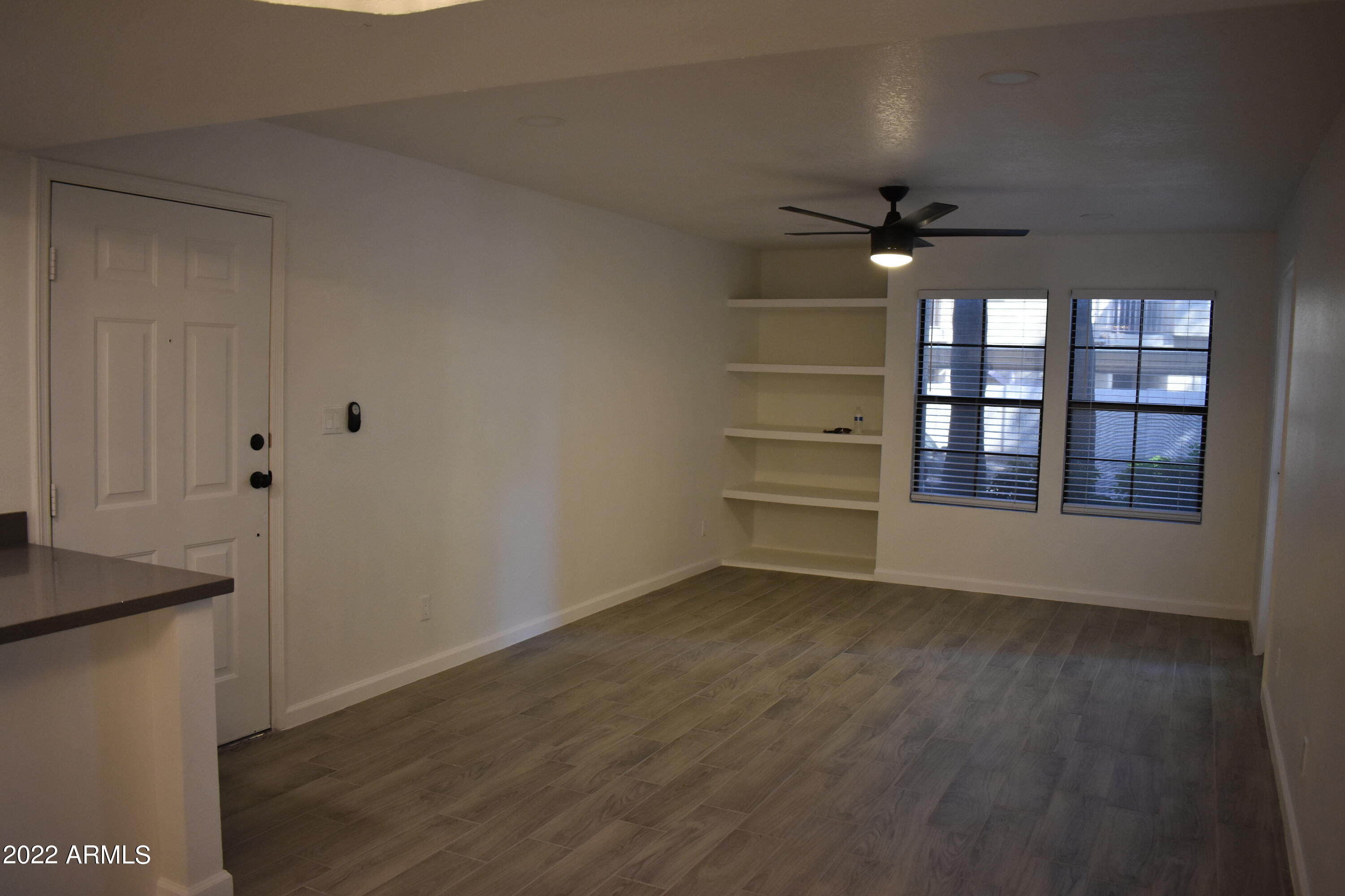 2855 South Ext Road, Unit 135 Mesa, AZ 85210 - Photo 3 of 19 an empty room with wooden floor and windows