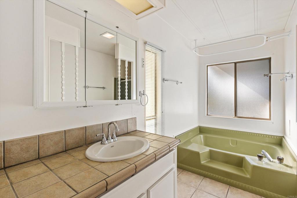 650 South Rancho Santa Fe Road, Unit 312 San Marcos, CA 92078 - Photo 23 of 53 a bathroom with a granite countertop sink and a mirror