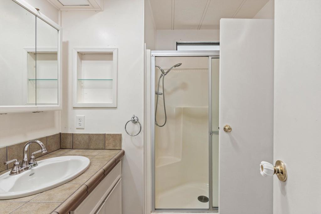 650 South Rancho Santa Fe Road, Unit 312 San Marcos, CA 92078 - Photo 27 of 53 a bathroom with a granite countertop shower sink vanity and mirror
