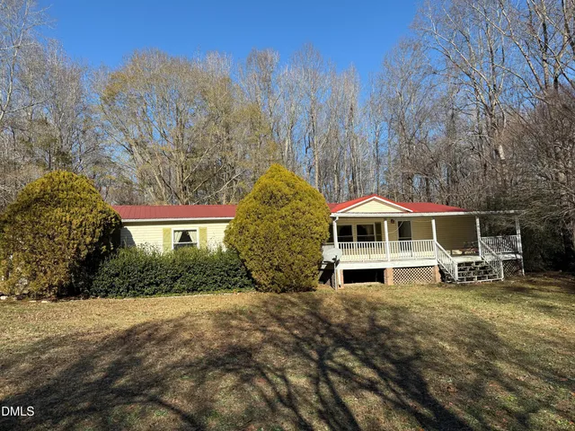 a view of a house with a yard and large trees
