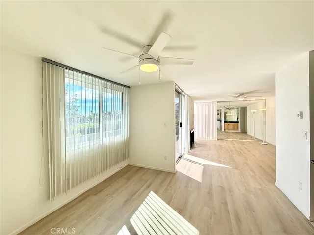 a view of an empty room with kitchen and a window