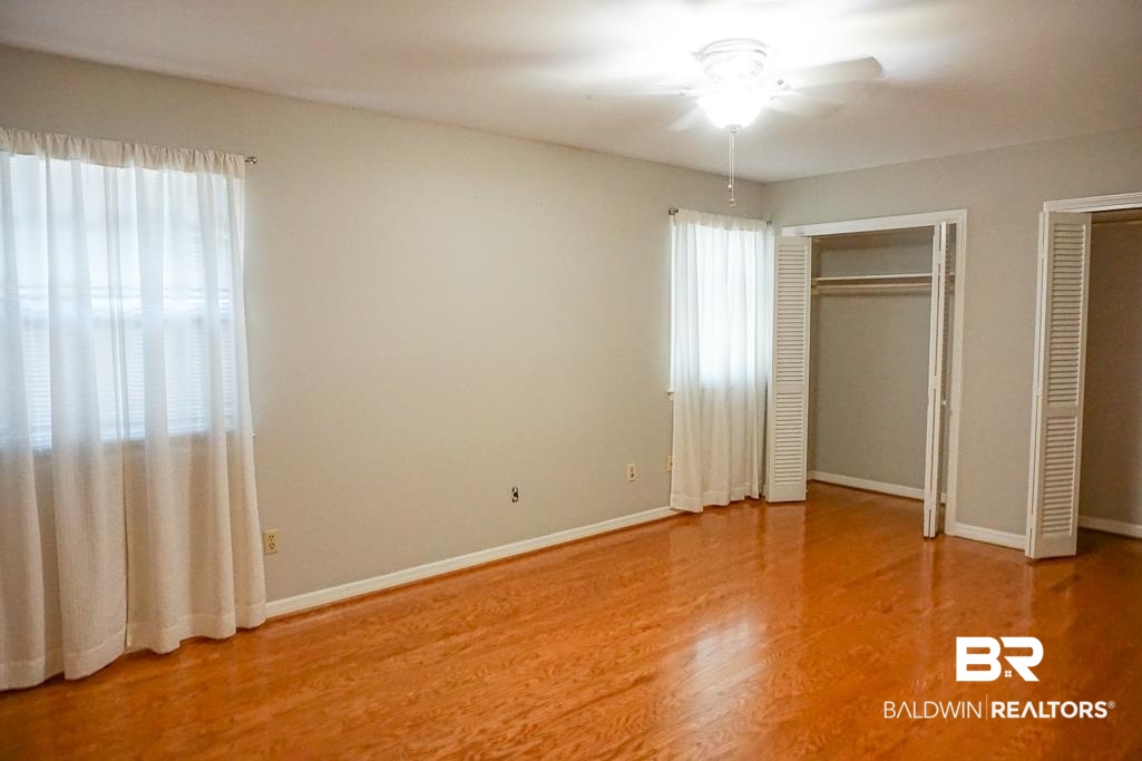 255 Suffolk Road Mobile, AL 36608 - Photo 26 of 29 Unfurnished bedroom with multiple closets, light wood-style flooring, and a ceiling fan