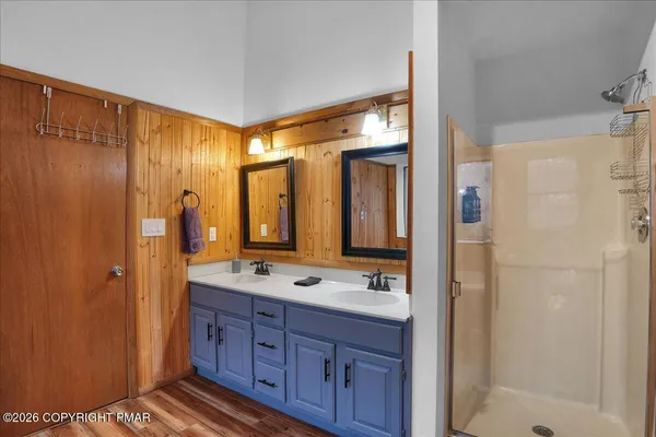 a bathroom with a double vanity sink a mirror and a shower