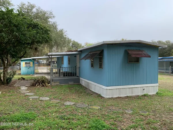 a backyard of a house with potted plants and large tree