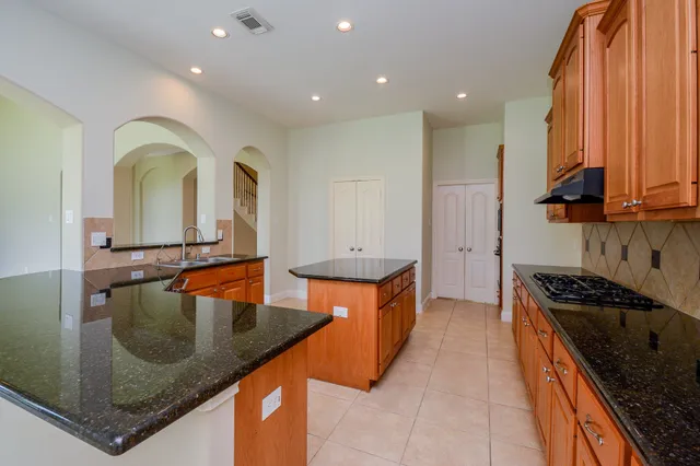 a kitchen with stainless steel appliances granite countertop a sink a stove and a wooden cabinets