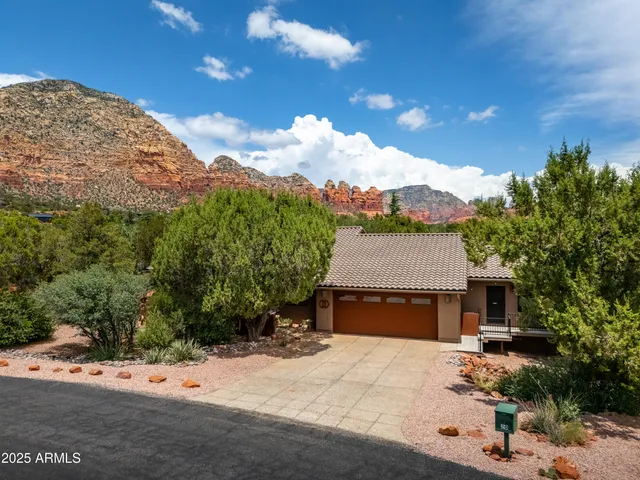 a front view of a house with a yard and mountain view in back