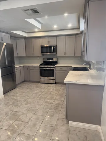 a kitchen with stainless steel appliances a sink a stove top oven a counter space and cabinets