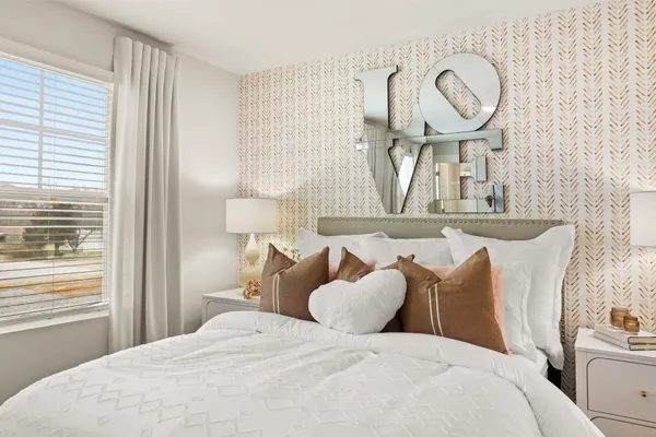 a bedroom with a bed and a potted plant on the dresser