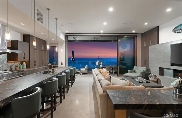a kitchen with stainless steel appliances kitchen island granite countertop a sink a counter top space and living room view