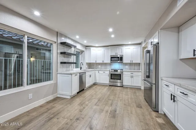 a kitchen with cabinets stainless steel appliances and wooden floor
