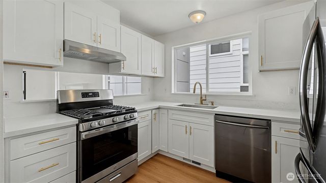 a kitchen with granite countertop cabinets stainless steel appliances and wooden floor
