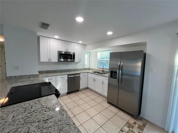 a kitchen with granite countertop a refrigerator sink and microwave
