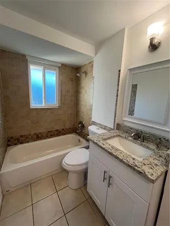 a bathroom with a granite countertop sink a toilet a mirror and bathtub